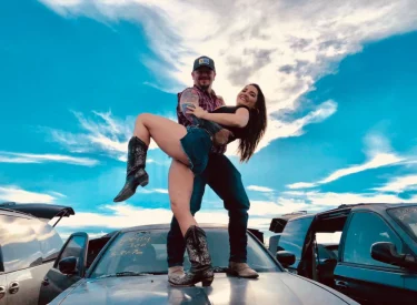Man holding woman on top of car